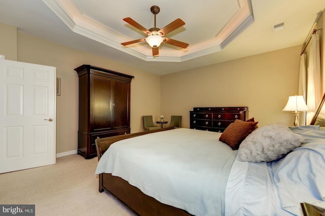 bedroom with light carpet, visible vents, a tray ceiling, and ornamental molding