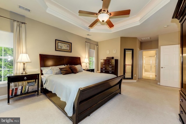 bedroom with a tray ceiling, light carpet, visible vents, and ornamental molding