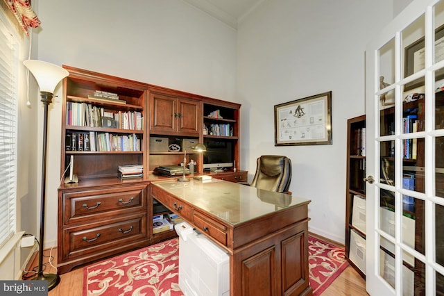 office space with french doors, baseboards, crown molding, and light wood-style floors