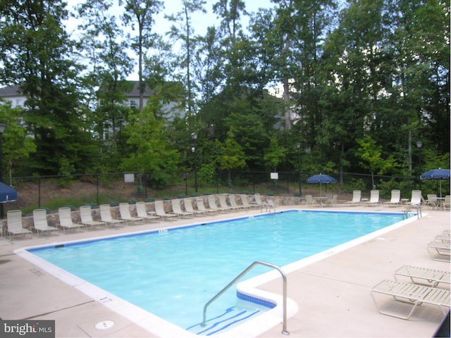 pool with a patio area and fence