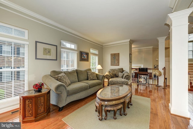 living room with visible vents, baseboards, decorative columns, crown molding, and light wood-type flooring