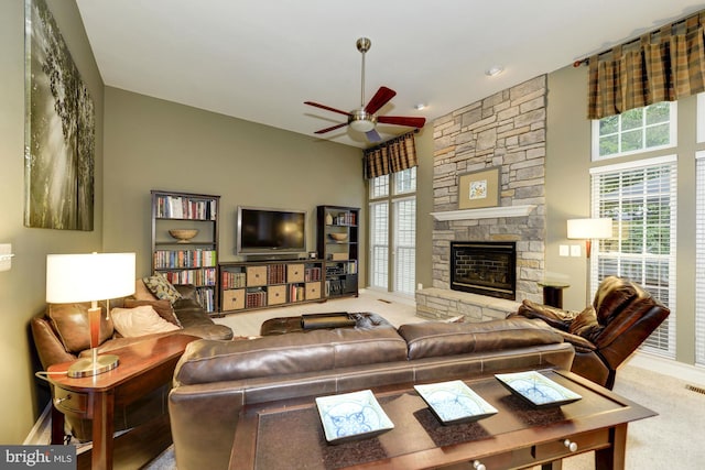 living room with a stone fireplace, plenty of natural light, a ceiling fan, and a towering ceiling