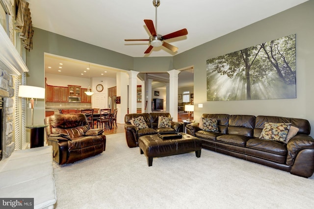 living room featuring decorative columns, light carpet, ceiling fan, and a fireplace