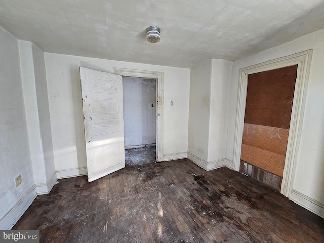 empty room with baseboards and wood-type flooring