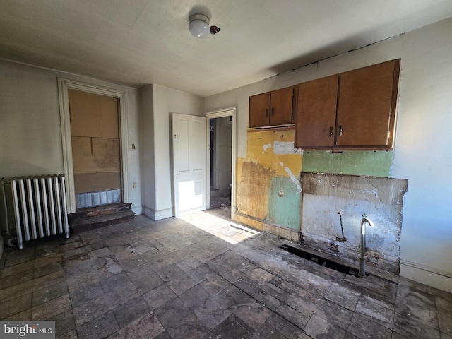 kitchen featuring brown cabinetry, baseboards, and radiator heating unit