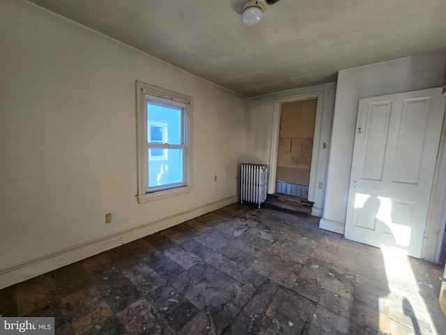 interior space featuring stone finish floor, radiator, and baseboards