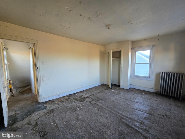 unfurnished bedroom with a closet, radiator heating unit, and baseboards