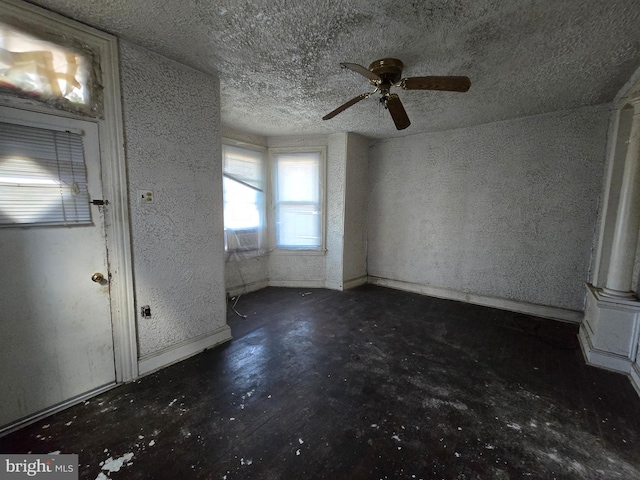 foyer entrance with baseboards, concrete flooring, and a textured ceiling