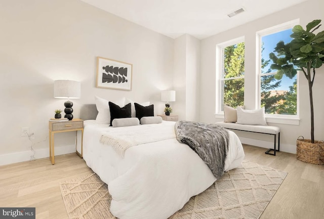 bedroom featuring visible vents, light wood-type flooring, and baseboards