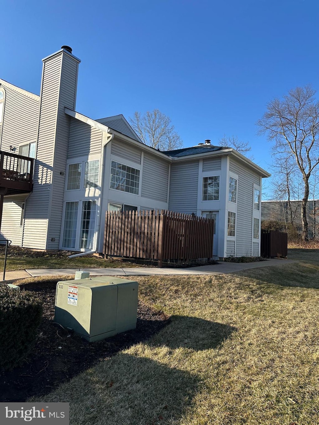 back of house with a lawn, a chimney, and fence