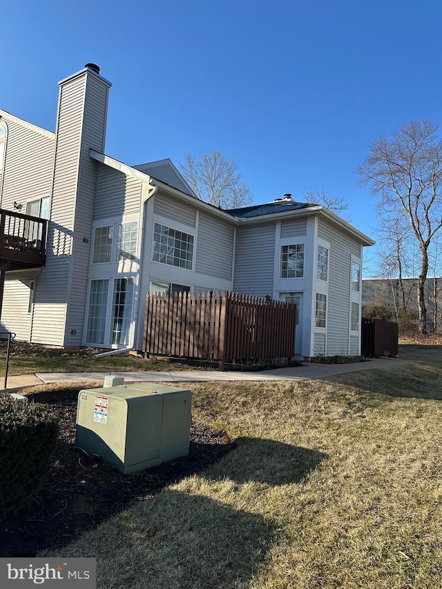 back of house with a lawn, a chimney, and fence