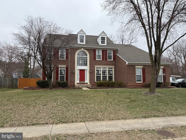 view of front of property with brick siding, a front lawn, and fence