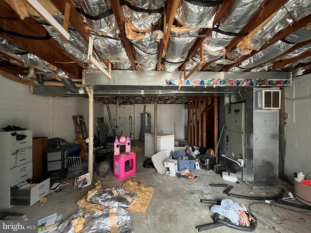 unfinished below grade area featuring electric water heater and concrete block wall