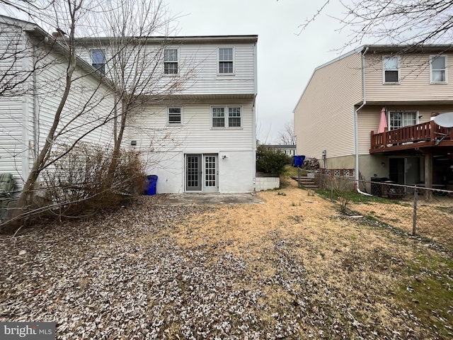 rear view of property featuring a deck, french doors, and fence