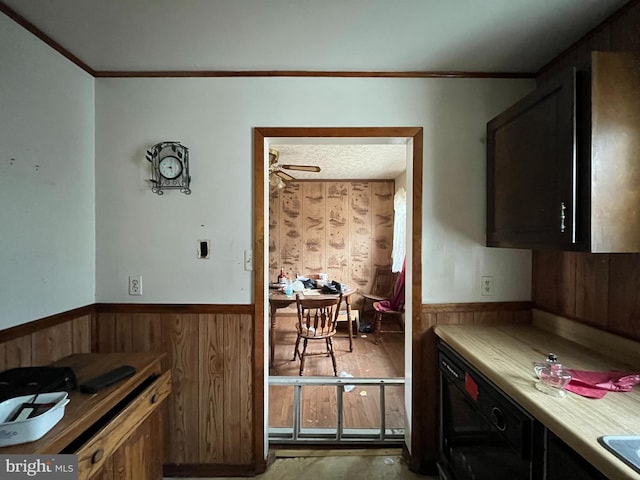 kitchen featuring a wainscoted wall, wooden walls, ornamental molding, and light countertops