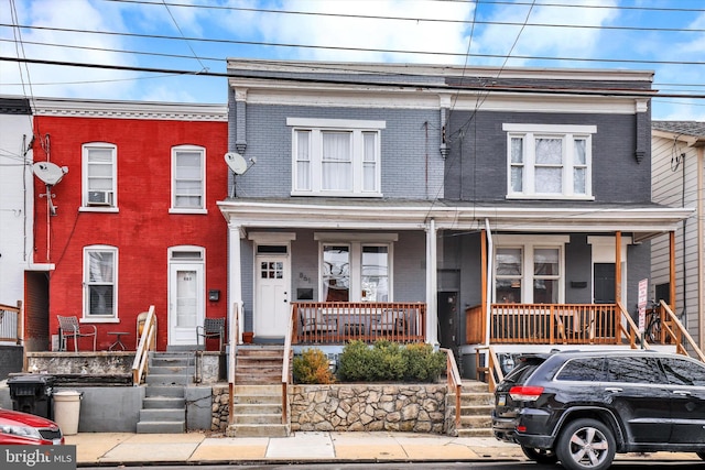 townhome / multi-family property with brick siding and covered porch