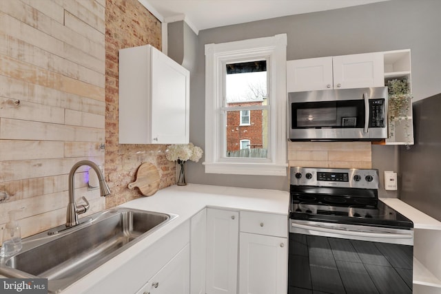 kitchen featuring light countertops, decorative backsplash, white cabinets, stainless steel appliances, and a sink