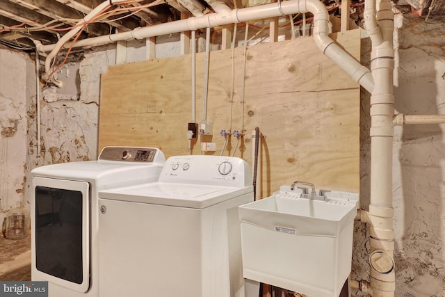 washroom featuring washer and clothes dryer, laundry area, and a sink