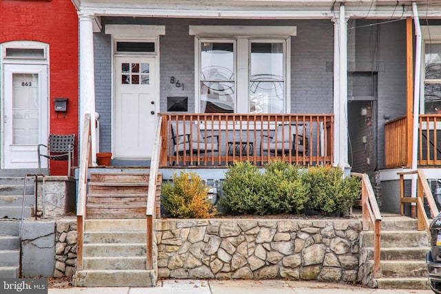 property entrance with brick siding and covered porch