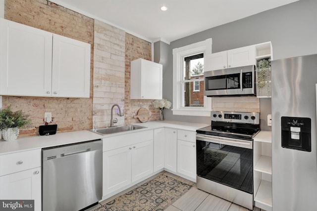 kitchen with backsplash, light countertops, stainless steel appliances, white cabinetry, and a sink