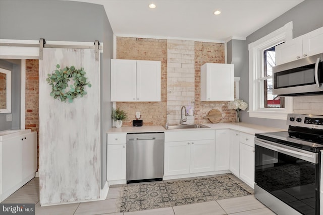 kitchen featuring white cabinetry, stainless steel appliances, light countertops, and a sink