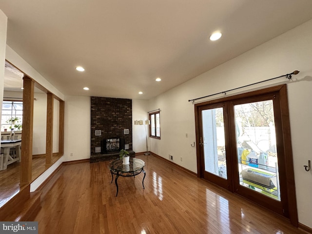 unfurnished living room featuring a brick fireplace, recessed lighting, wood finished floors, and baseboards