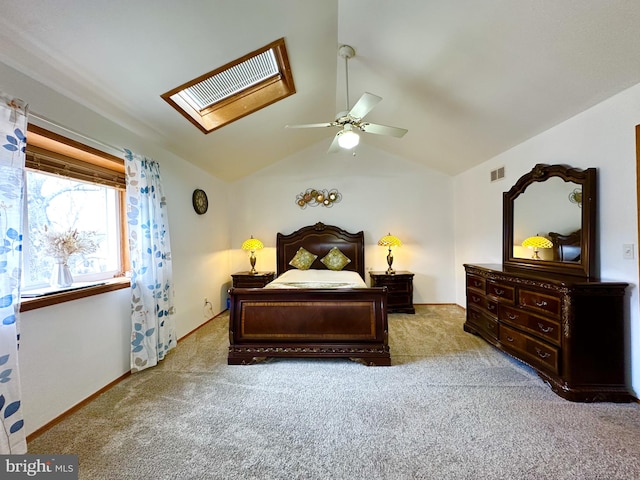 carpeted bedroom featuring visible vents, vaulted ceiling with skylight, baseboards, and ceiling fan