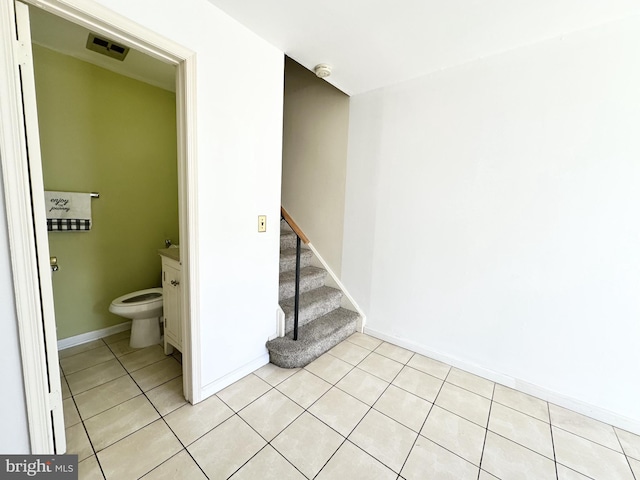 stairway with visible vents, baseboards, and tile patterned flooring