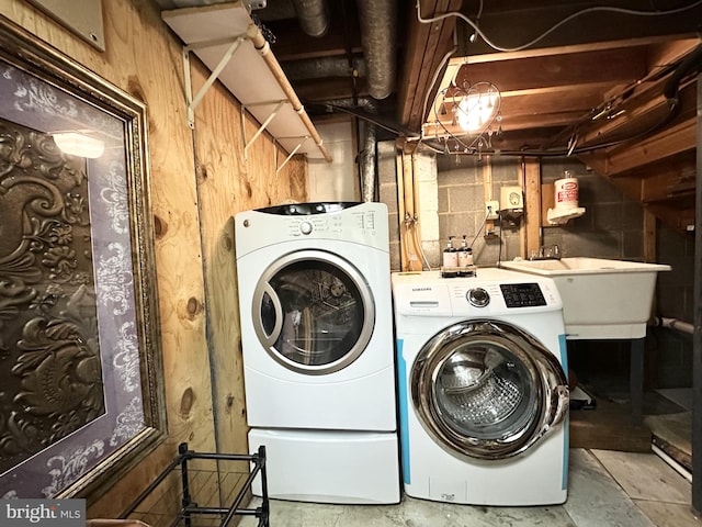 washroom featuring laundry area, washing machine and dryer, and a sink