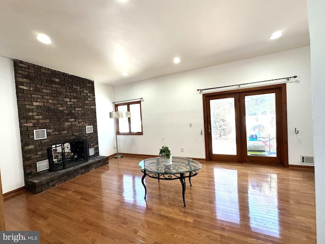 living room featuring visible vents, a fireplace, baseboards, and wood finished floors