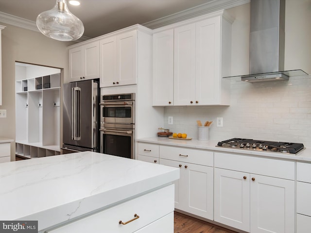 kitchen with white cabinets, appliances with stainless steel finishes, crown molding, wall chimney exhaust hood, and tasteful backsplash