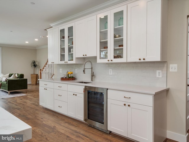 kitchen with wine cooler, light countertops, crown molding, and a sink