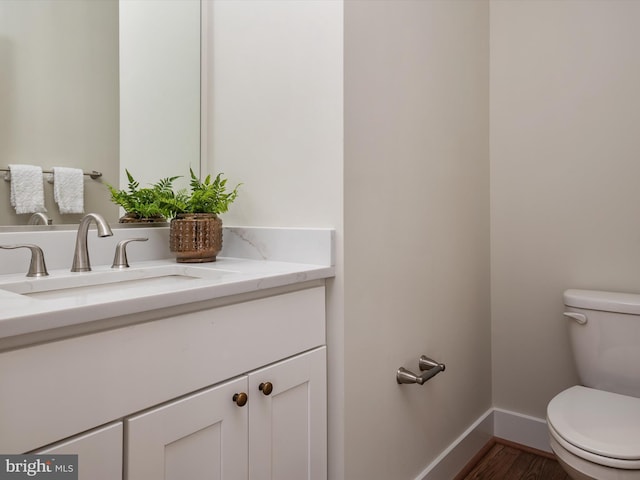 bathroom with baseboards, toilet, wood finished floors, and vanity