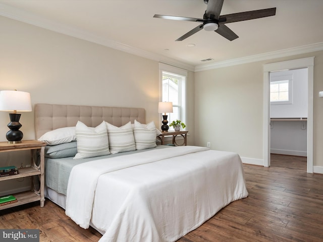 bedroom featuring a ceiling fan, wood finished floors, visible vents, baseboards, and crown molding