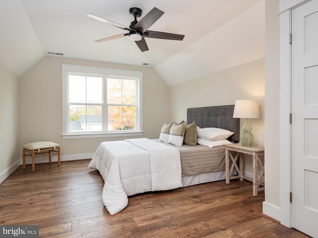 bedroom featuring visible vents, a ceiling fan, wood finished floors, baseboards, and vaulted ceiling