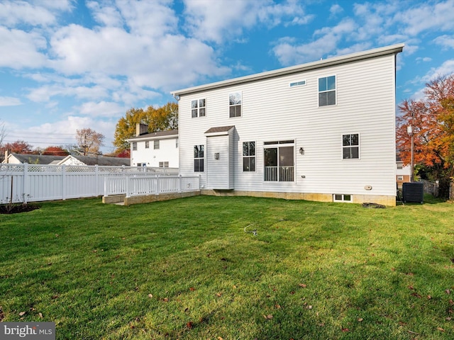 rear view of property featuring central air condition unit, a lawn, and fence