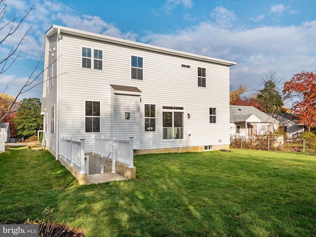 rear view of house featuring a lawn and fence