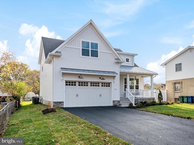 view of front of home featuring a front yard, driveway, a standing seam roof, an attached garage, and covered porch