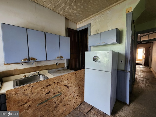 kitchen with an ornate ceiling, freestanding refrigerator, and a sink