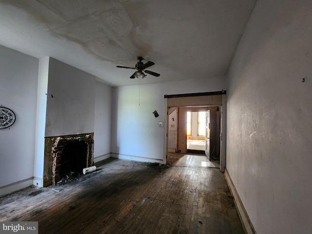 unfurnished living room with ceiling fan, baseboards, hardwood / wood-style floors, and a fireplace