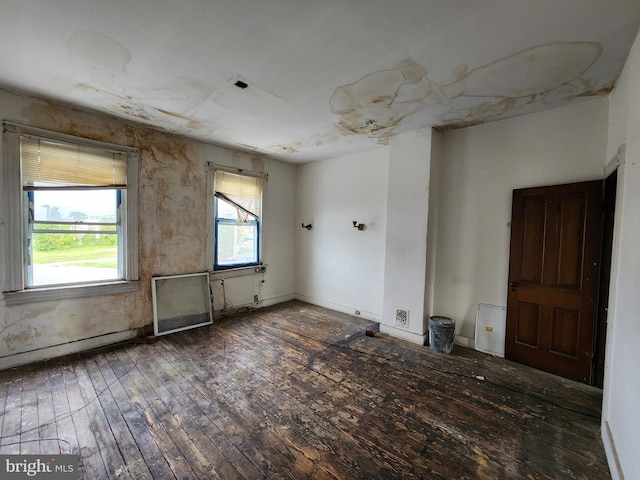 spare room featuring baseboards and wood-type flooring