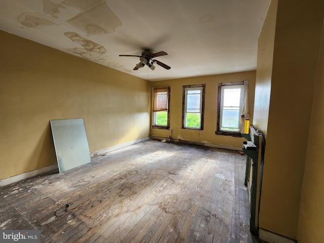 empty room featuring a ceiling fan, baseboards, and hardwood / wood-style floors