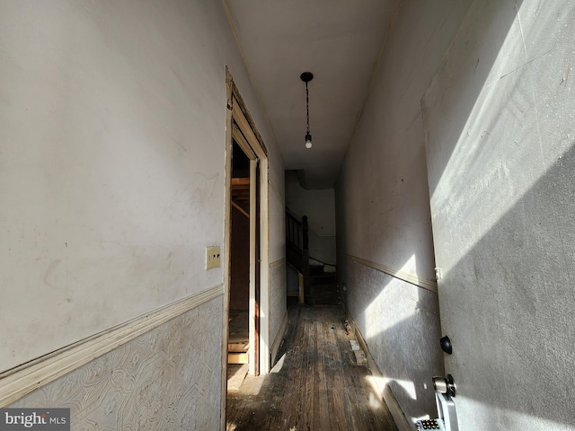 corridor with a wainscoted wall and wood finished floors