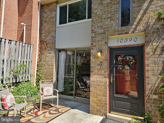 entrance to property with fence and brick siding