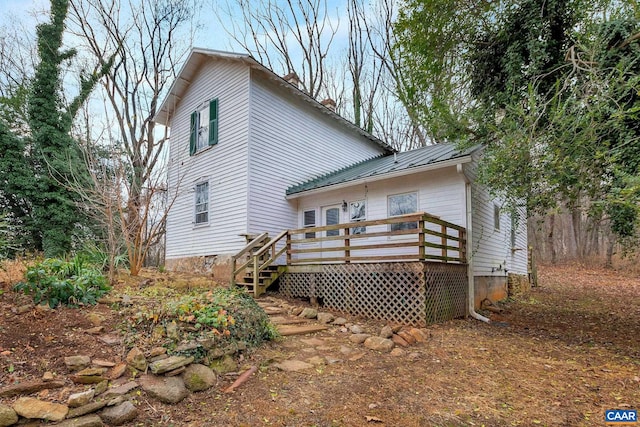 rear view of property featuring a wooden deck, metal roof, and a standing seam roof