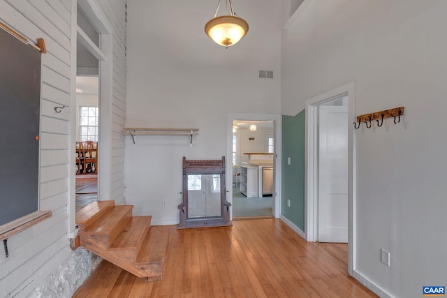 interior space featuring visible vents, plenty of natural light, a high ceiling, and hardwood / wood-style floors