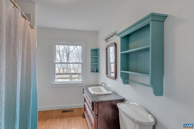 bathroom featuring visible vents, baseboards, toilet, vanity, and wood-type flooring