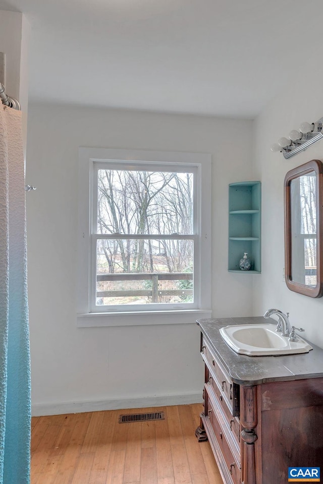 bathroom featuring visible vents, baseboards, wood finished floors, and vanity