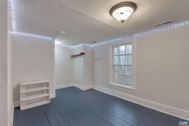 unfurnished room featuring visible vents, baseboards, and dark wood finished floors