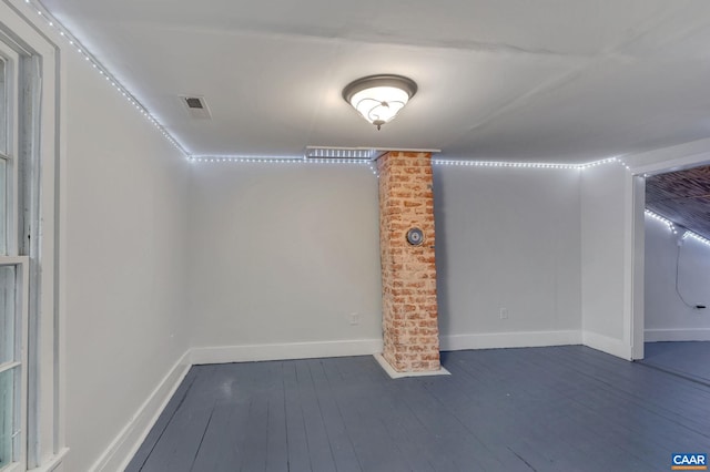 basement featuring dark wood-style floors, visible vents, and baseboards